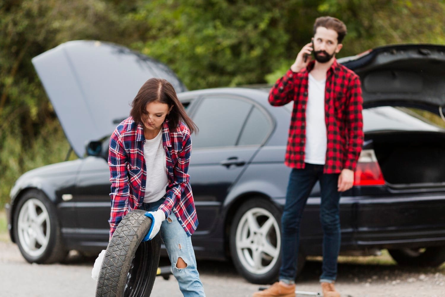 woman holding spare tire man talking phone woman holding spare tire man talking phone